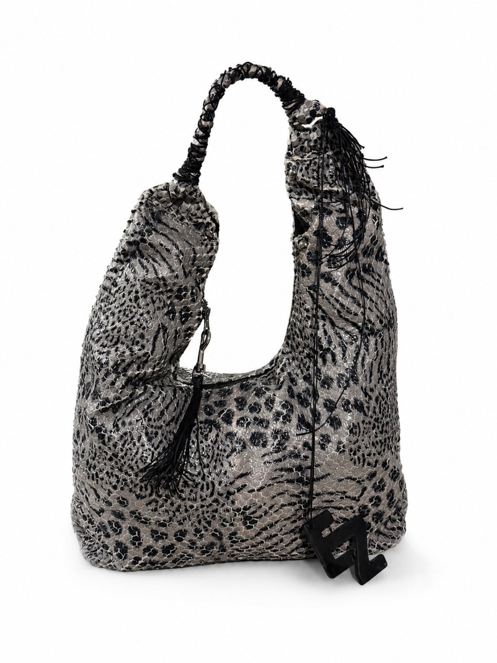 A slouchy shoulder bag with a black and gray animal print pattern, featuring a braided shoulder strap, black tassels, and a black elnze logo charm.
