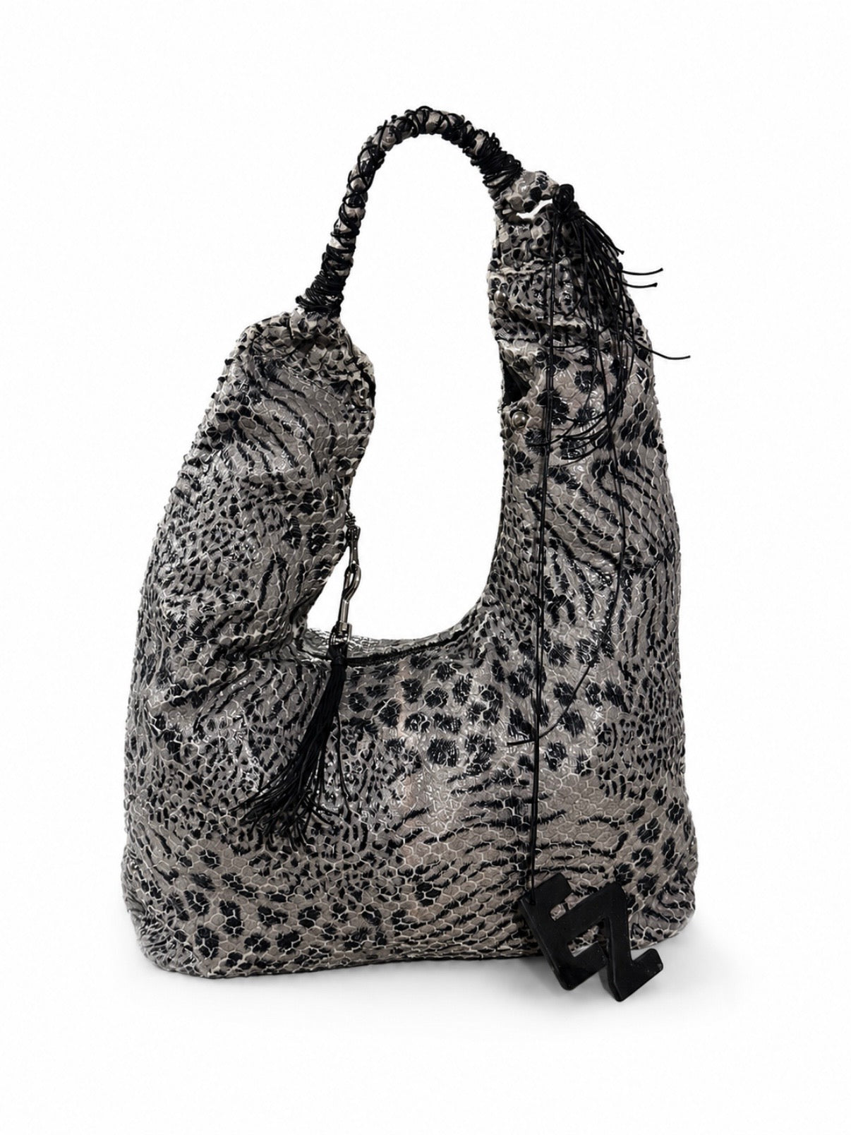 A slouchy shoulder bag with a black and gray animal print pattern, featuring a braided shoulder strap, black tassels, and a black elnze logo charm.